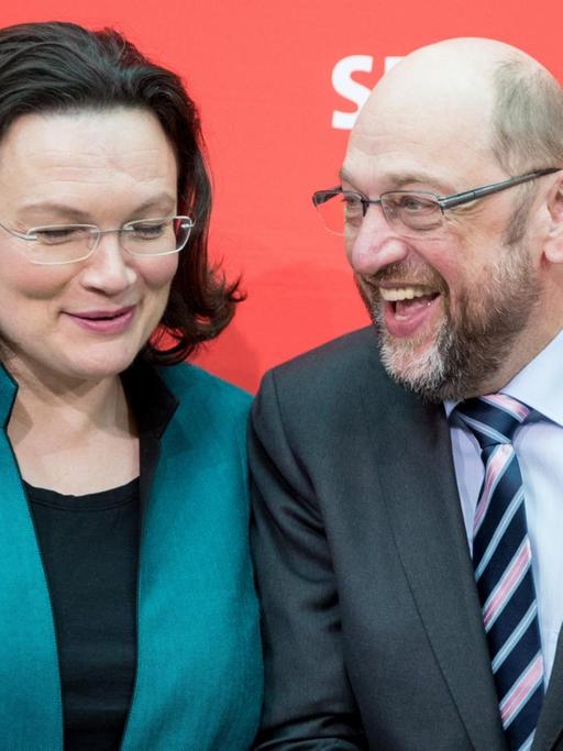 Nahles und Schulz stehen vor einer roten Wand mit dem SPD-Logo und lachen sich zu.