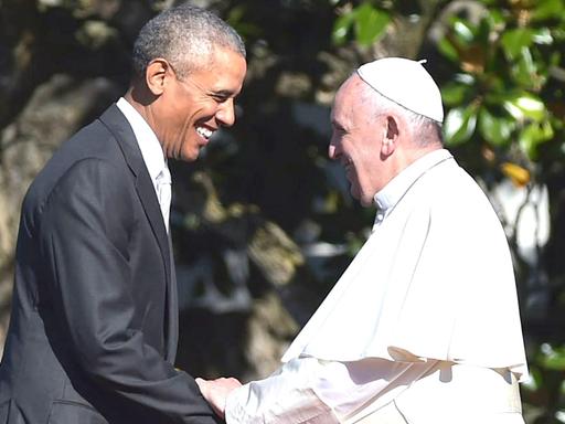 US-Präsident Barack Obama und Papst Franziskus halten sich an den Händen und strahlen.