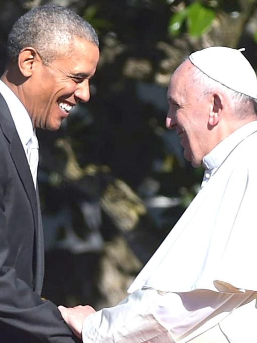 US-Präsident Barack Obama und Papst Franziskus halten sich an den Händen und strahlen.