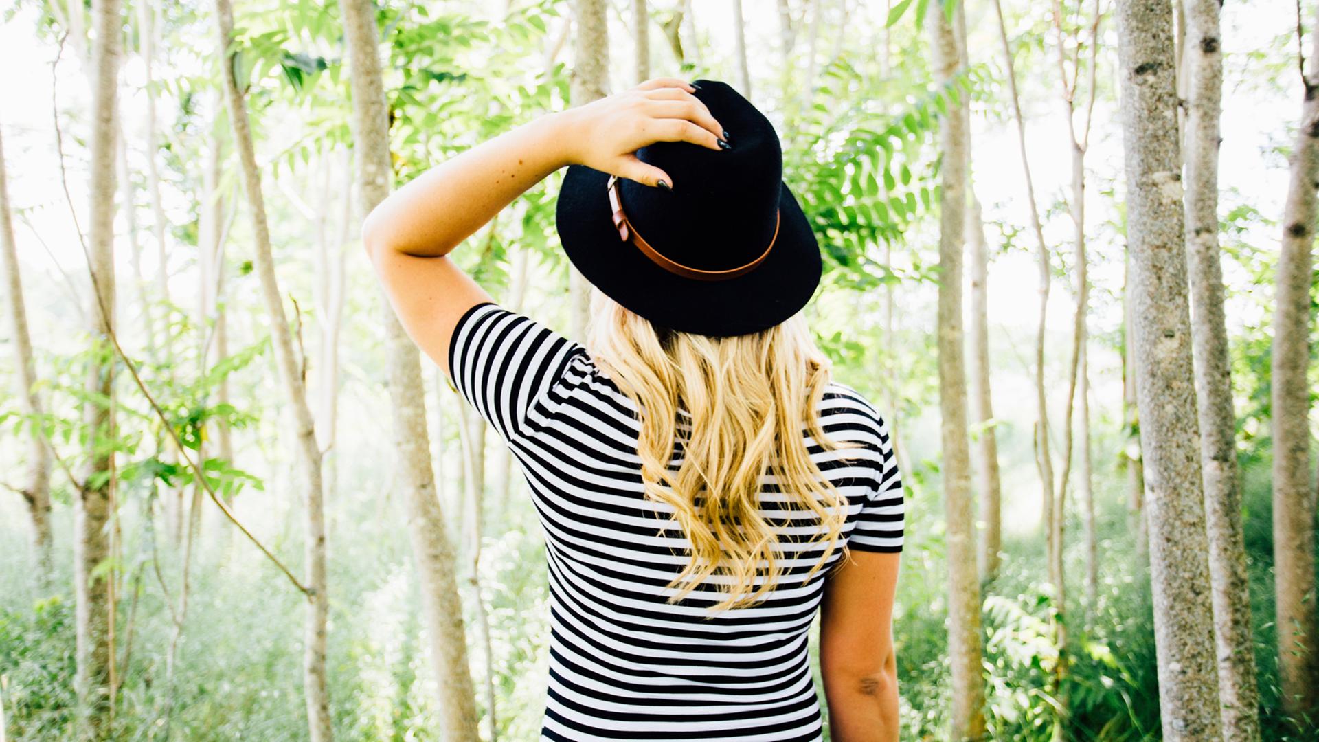 Eine Frau in einem gestreiften Shirt steht in einem Wald. Eine Frau in einem gestreiften Shirt steht in einem Wald.