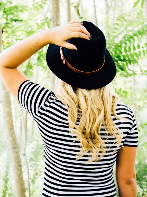 Eine Frau in einem gestreiften Shirt steht in einem Wald.