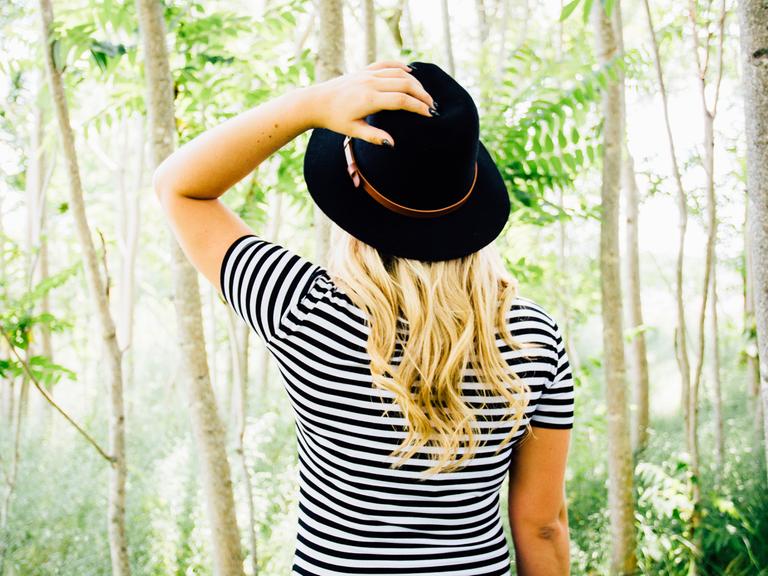 Eine Frau in einem gestreiften Shirt steht in einem Wald.