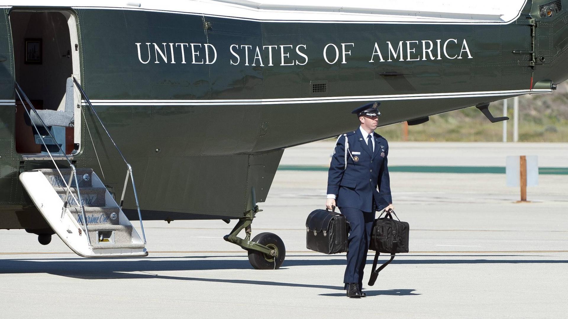 Ein Adjutant mit dem "Atomkoffer" verlässt am 13.3.2015 den Hubschrauber des US-Präsidenten. Der Koffer, auch "The Football" genannt, befindet sich jederzeit in der Nähe des Amtsinhabers. Auch die Staatsführer anderer Atomstaaten haben stets ähnliche Systeme bei sich. Ein Adjutant mit dem "Atomkoffer" verlässt am 13.3.2015 den Hubschrauber des US-Präsidenten. Der Koffer, auch "The Football" genannt, befindet sich jederzeit in der Nähe des Amtsinhabers. Auch die Staatsführer anderer Atomstaaten haben stets ähnliche Systeme bei sich.