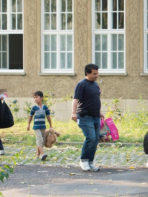Flüchtlinge laufen an einer Erstaufnahmeeinrichtung entlang