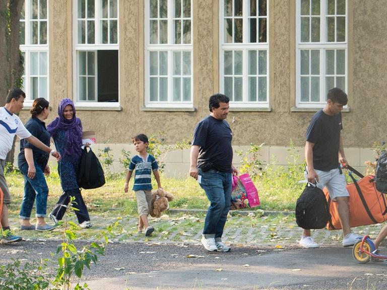 Flüchtlinge laufen an einer Erstaufnahmeeinrichtung entlang