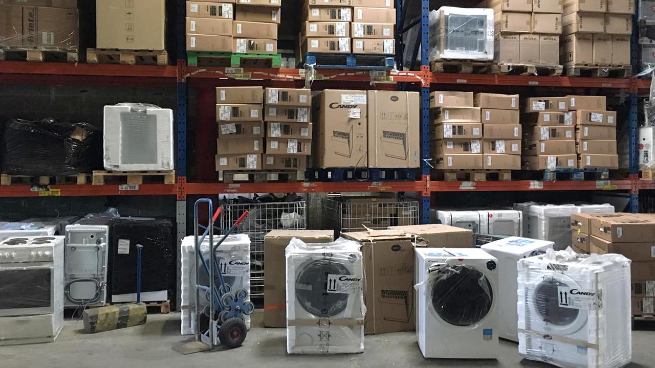 Waschmaschinen und Elektroherde vor und in großen Lagerregalen Waschmaschinen und Elektroherde vor und in großen Lagerregalen