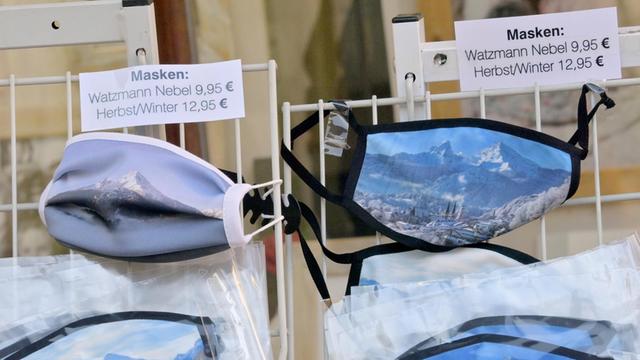 Berchtesgaden: Gesichtsmasken mit einem Motiv vom Watzmann hängen in der Fußgängerzone in einem Geschäft aus.