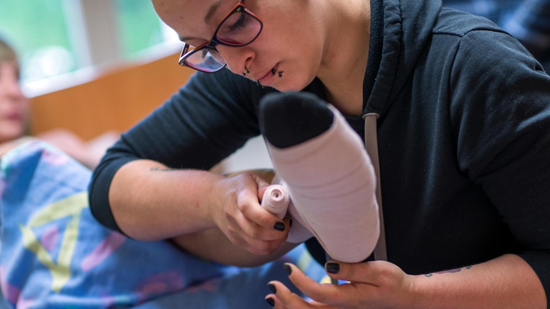 Eine Pflegerin legt einen Thrombose-Verband an. Eine Pflegerin legt einen Thrombose-Verband an.