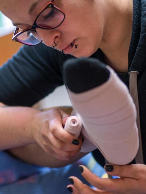 Eine Pflegerin legt einen Thrombose-Verband an.