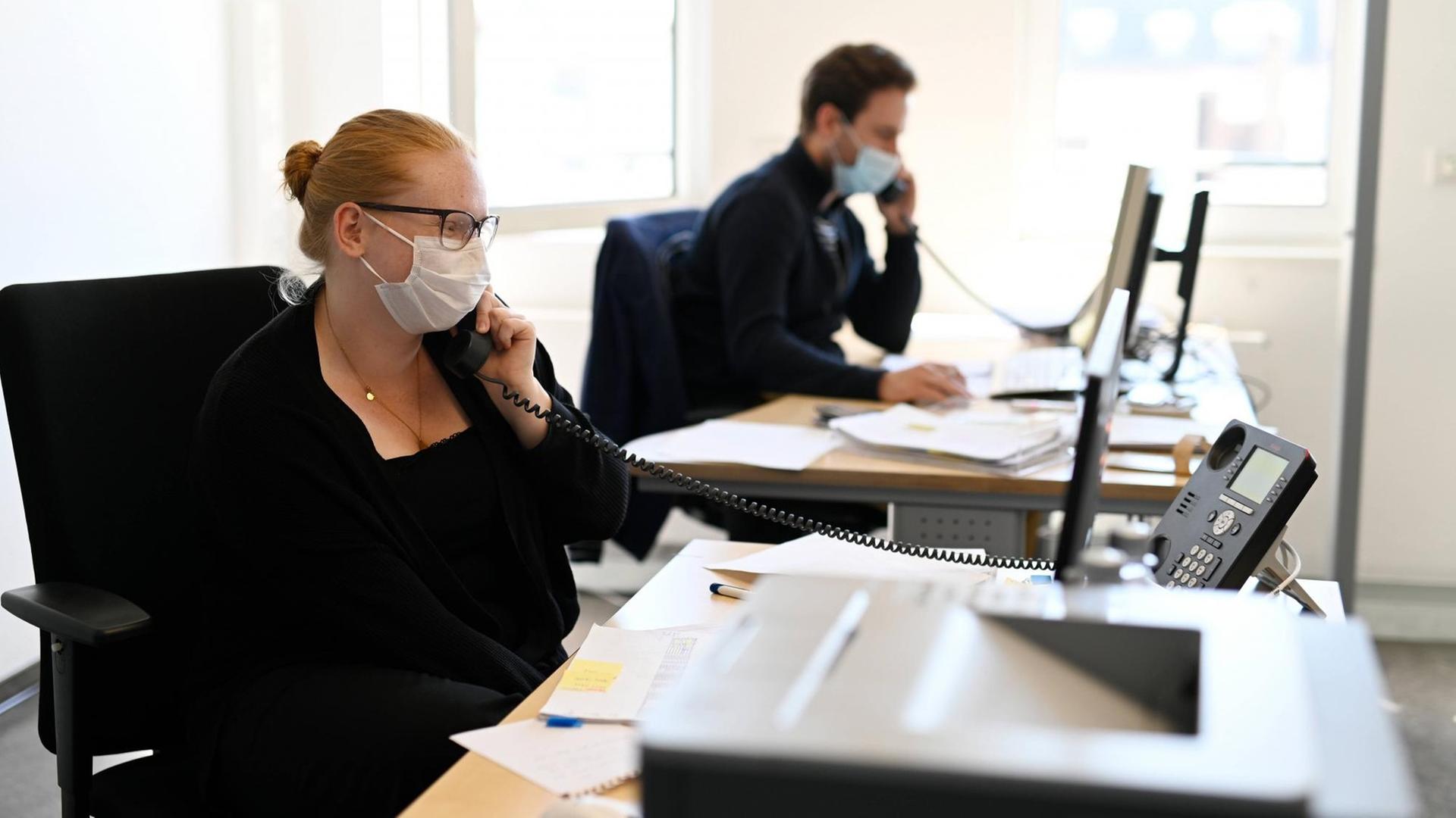 Eine Frau und eine Mann sitzen in einem Büro und telefonieren Eine Frau und eine Mann sitzen in einem Büro und telefonieren