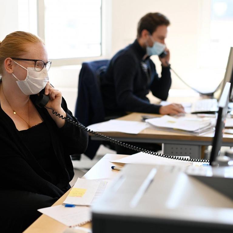 Eine Frau und eine Mann sitzen in einem Büro und telefonieren