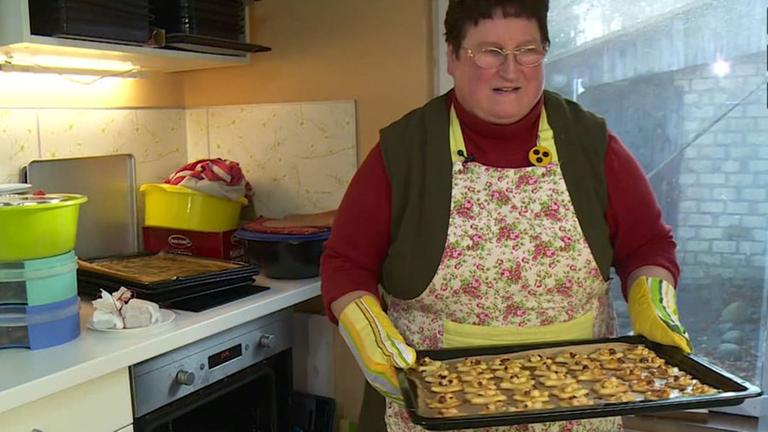 Die blinde Bäckerin Doris Hollnagel hält in ihrer Küche ein Blech voller Plätzchen in den Händen. Die blinde Bäckerin Doris Hollnagel hält in ihrer Küche ein Blech voller Plätzchen in den Händen.