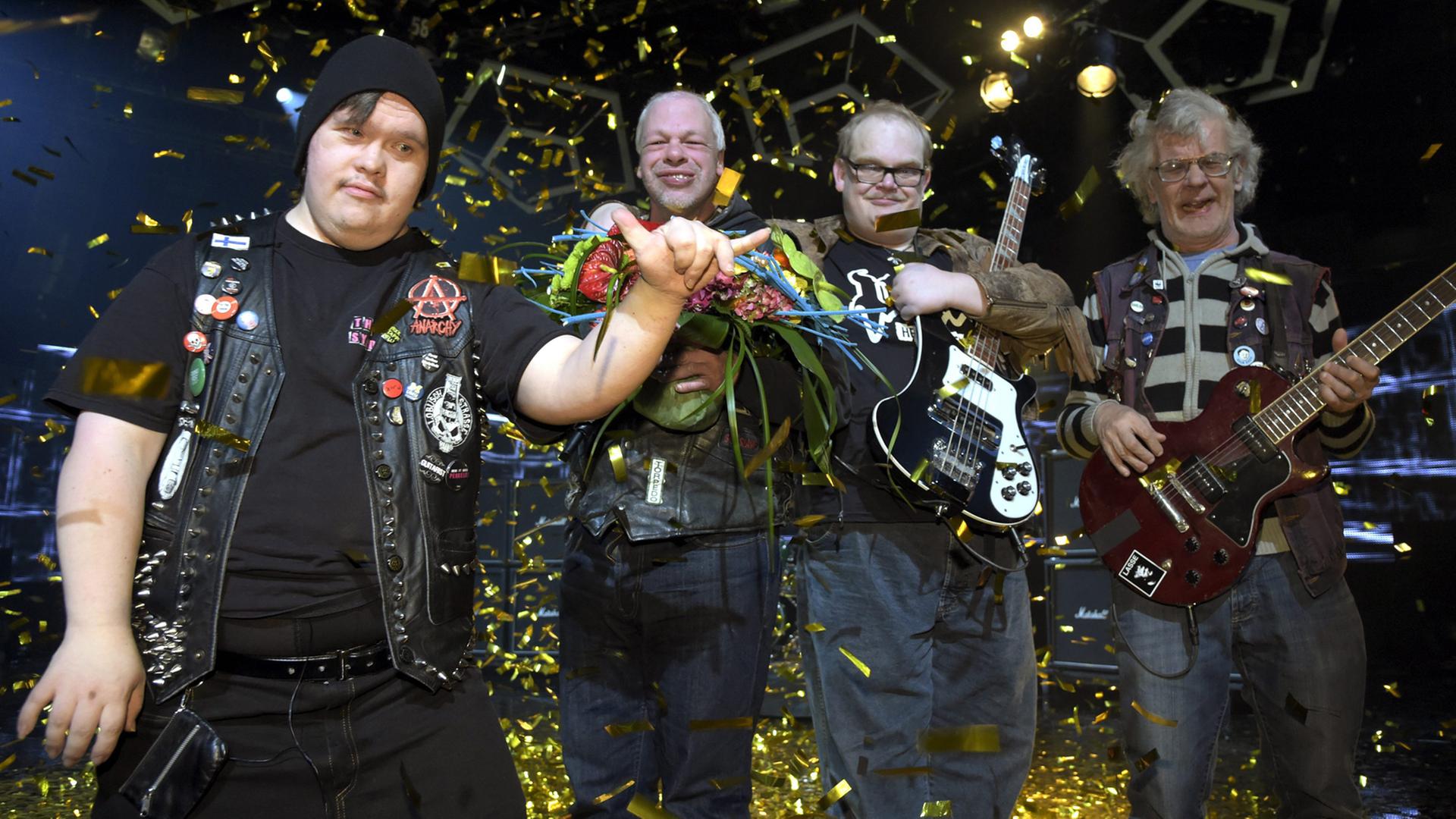 Die Band jubelt auf der Bühne ihm Glitzer-Regen Die Band jubelt auf der Bühne ihm Glitzer-Regen