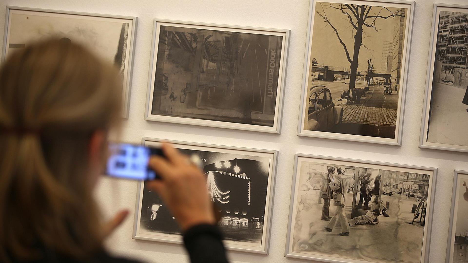 Eine Frau hält ihr Smartphone vor Fotografien aus der Serie «Köln» von Sigmar Polke. Die Ausstellung «Fotografien 70 - 80» von Sigmar Polke ist vom 27. Mai 2018 - 02. September 2018 im Museum Morsbroich zu sehen.