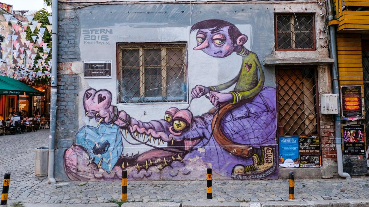 Grafitti im Restaurant- und Kneipenviertel Kapana in Plovdiv. Ein Junge sitzt auf einem Krokodil, das einen Diamanten im Maul hat. Grafitti im Restaurant- und Kneipenviertel Kapana in Plovdiv. Ein Junge sitzt auf einem Krokodil, das einen Diamanten im Maul hat.