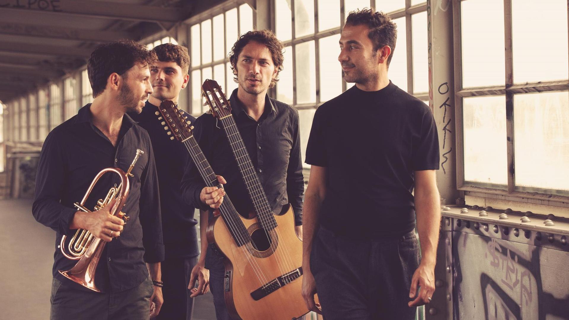Die Band Masaa steht mit ihren Instrumenten in einem industriellen Bau mit großen Fenstern. Die Band Masaa steht mit ihren Instrumenten in einem industriellen Bau mit großen Fenstern.