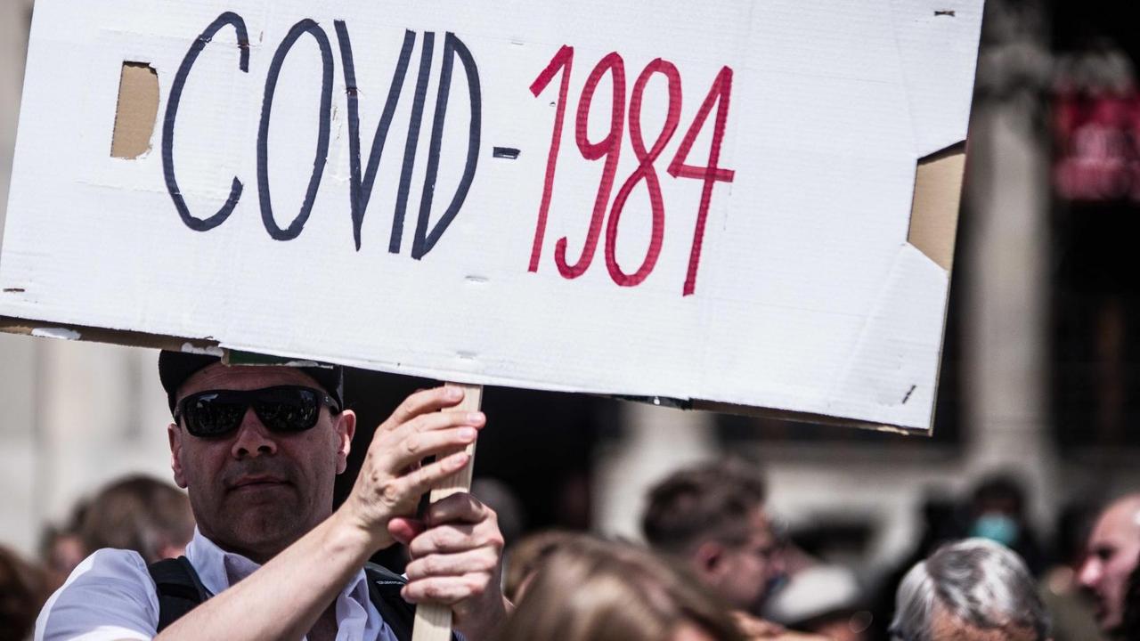 Ein Mann hält auf einer Hygienedemo in München ein Plakat mit der Aufschrift "COVID-1984" hoch