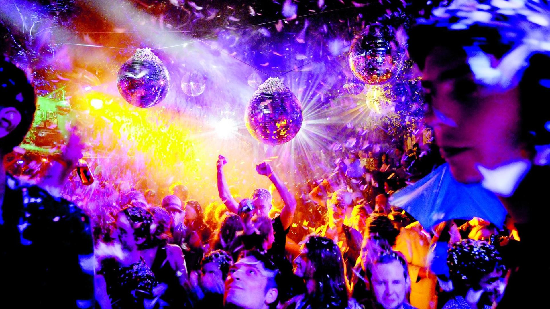 Im lila, gelb getauchten Licht reflektieren die Diskokugeln im Club. Im lila, gelb getauchten Licht reflektieren die Diskokugeln im Club.