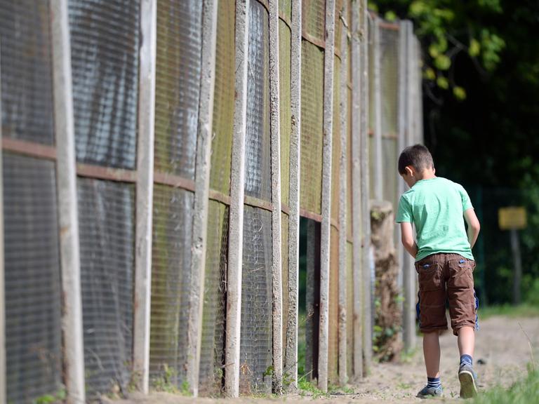 Ein Junge geht in Groß-Glienicke (Brandenburg) an einem Rest des Streckmetallzaunes der ehemaligen Berliner Mauer entlang.
