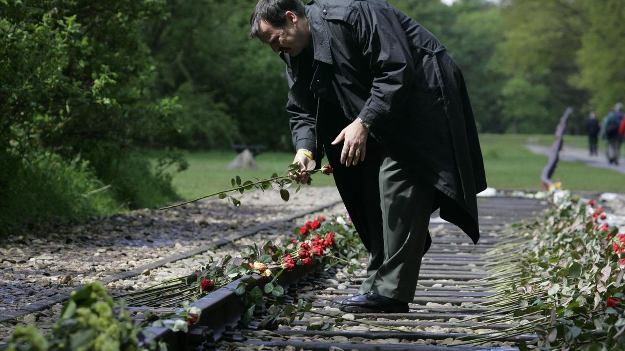 Ein Mann legt eine Rose auf den Gleisen des ehemaligen Konzentrationslagers Westerbork in den Niederlanden ab. Niederländische Jüdinnen und Juden wurden während des Zweiten Weltkriegs von dort aus in die Vernichtungslager der Nazis deportiert. 