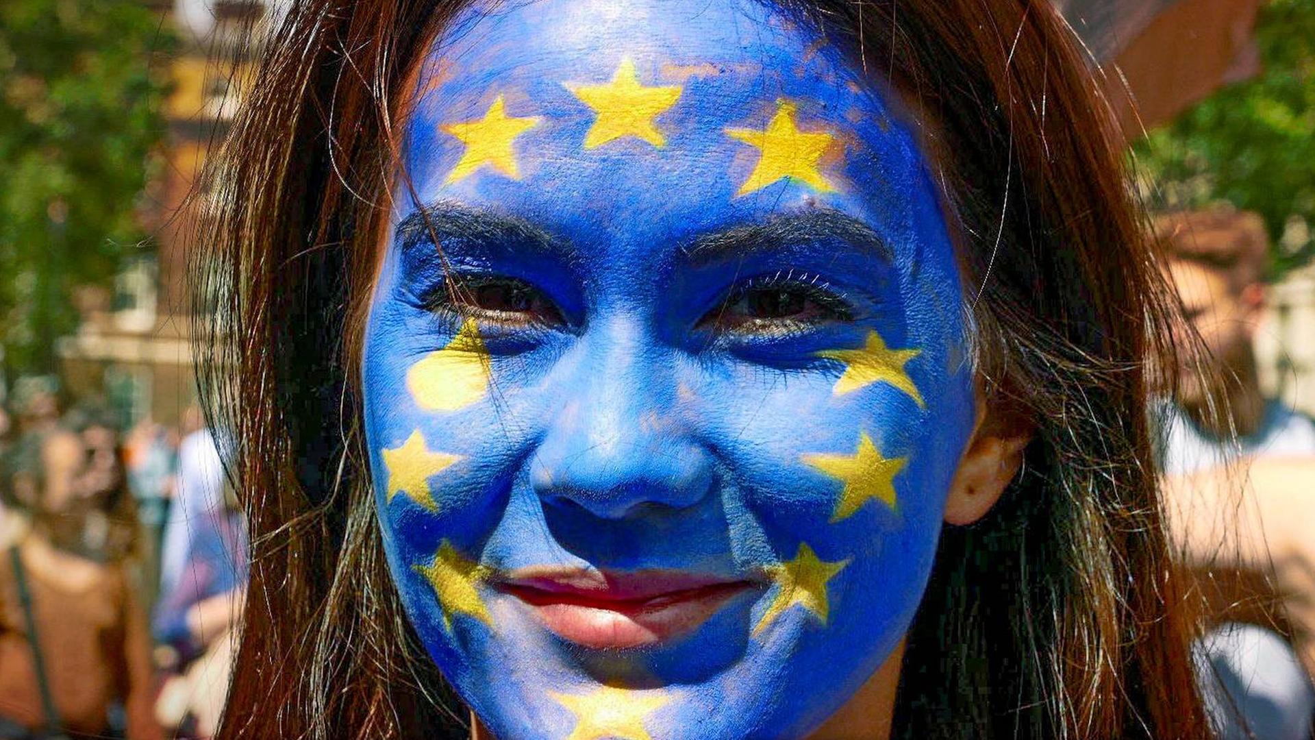 Eine Frau trägt die EU-Flagge im Gesicht.
