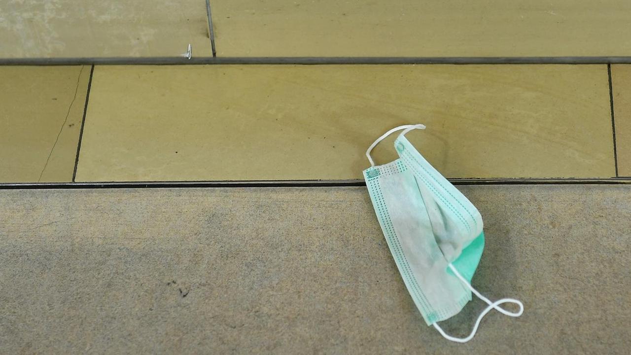 Eine Atemschutzmaske liegt auf dem Boden. Eine Atemschutzmaske liegt auf dem Boden.
