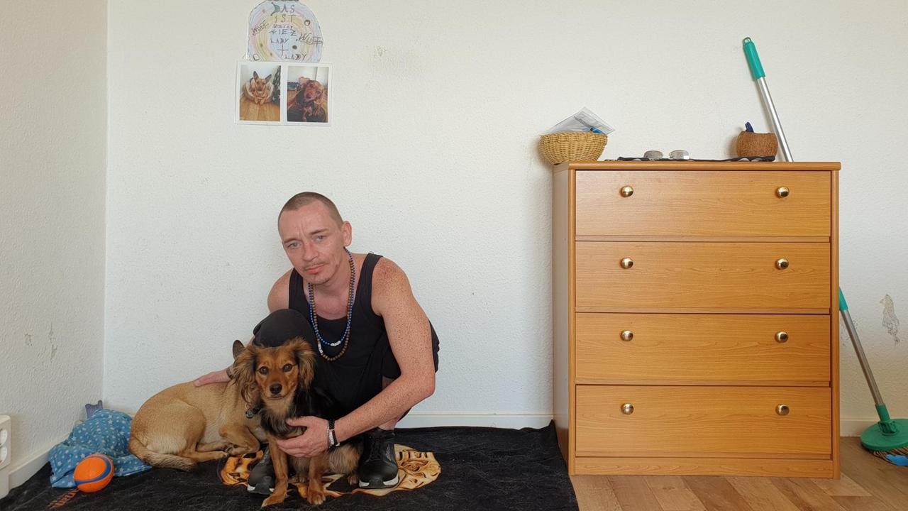 Benjamin sitzt in seiner Wohnung, die er über das Housing First Modellprojekt erhalten hat. Benjamin sitzt in seiner Wohnung, die er über das Housing First Modellprojekt erhalten hat.