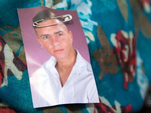 Eine Demonstrantin hat sich am 05.04.2014 in Berlin bei einer Demonstration zum Gedenken an den 22-jährigen Burak Bektas ein Portrait des Ermordeten an das Kopftuch gehängt.