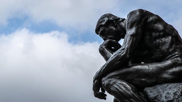 Die Plastik "Der Denker" ("Le Penseur") des Bildhauers Auguste Rodin ist vor einem wolkenverhangenen Himmel zu sehen.