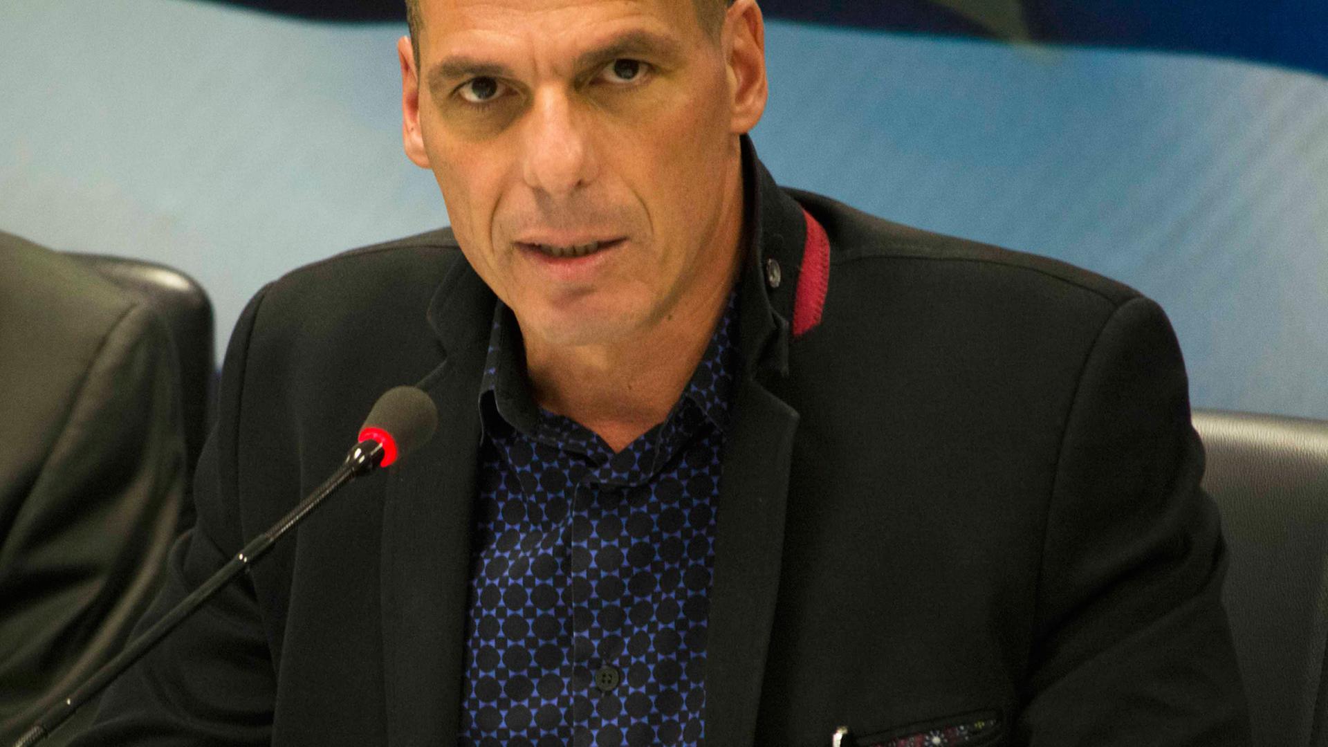 Yannis Varoufakis spricht an einem Mikrofon.