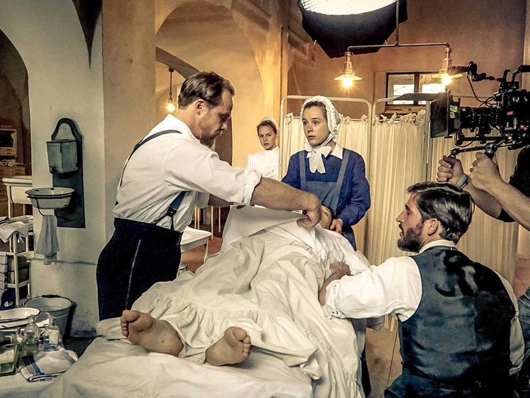 Am Filmset der historischen ARD-Krankenhausserie "Charité" mit sechs Folgen: die Schauspieler Matthias Koeberlin (Rolle Behring, l.), Klara Deutschmann (Rolle Therese; M.) und Christoph Bach (Rolle Ehrlich, 2.v.r.) sowie Kameramann Holly Fink (r.) .