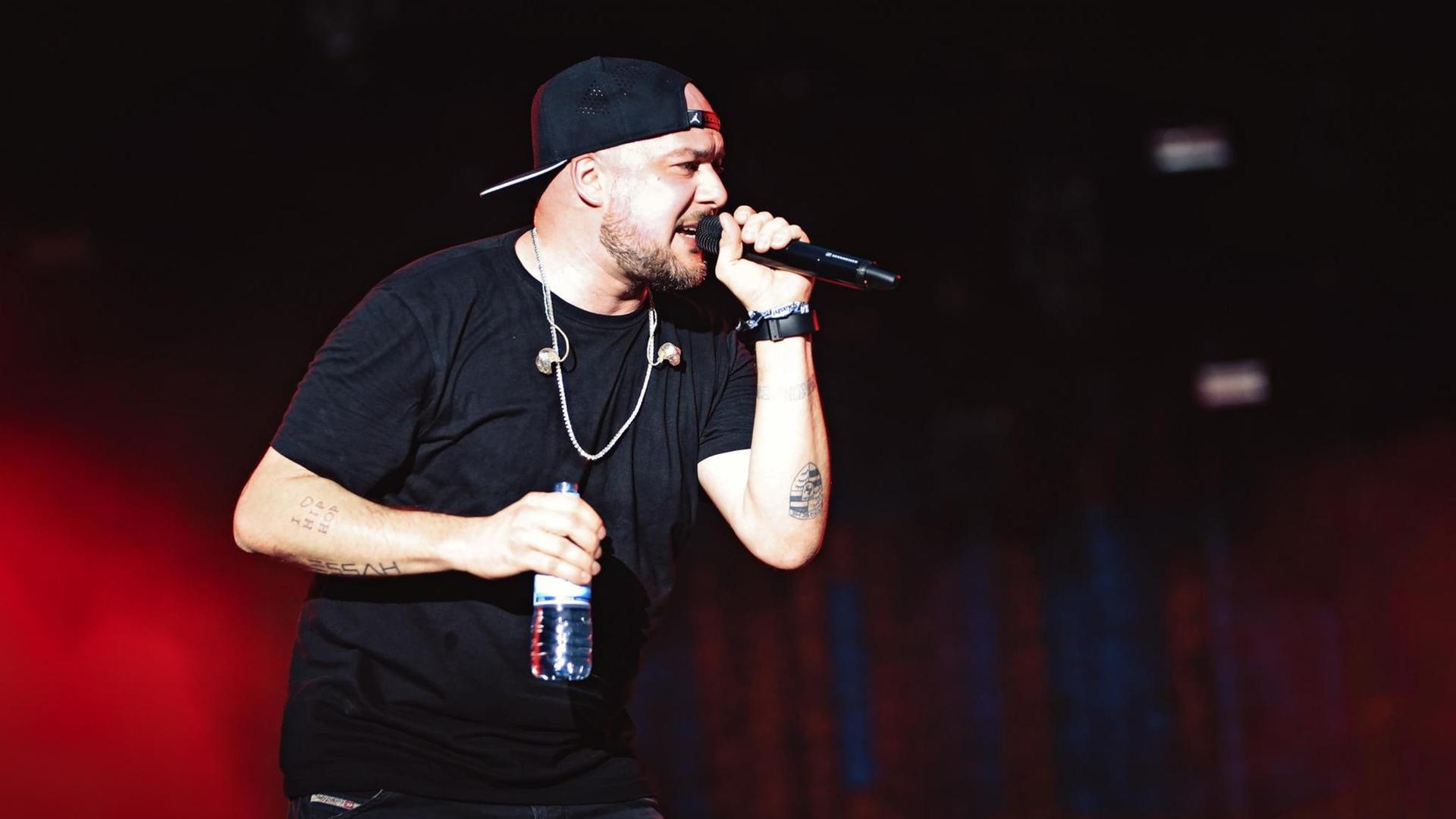 Kool Savas hält ein Mikrofon und rappt. Kool Savas hält ein Mikrofon und rappt.
