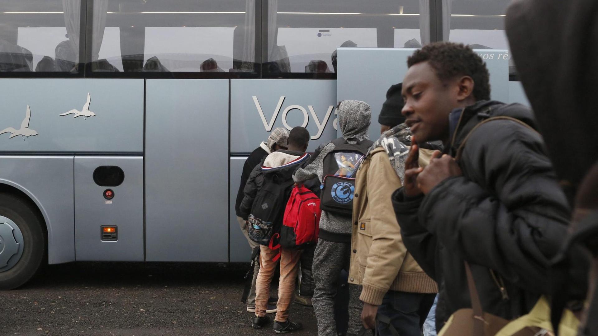 Migranten stehen in einer Schlange vor einem Bus und warten auf ihre Evakuierung kurz bevor die Räumung des Lagers in Calais beginnt. Migranten stehen in einer Schlange vor einem Bus und warten auf ihre Evakuierung kurz bevor die Räumung des Lagers in Calais beginnt.