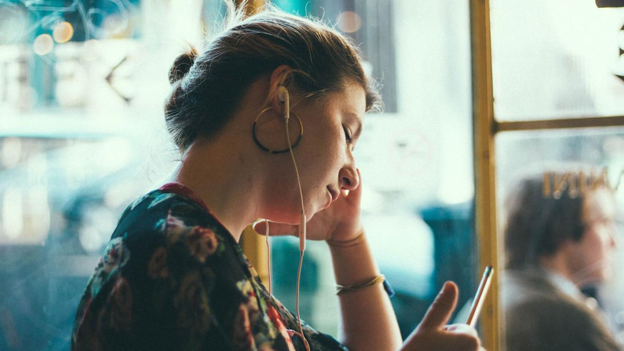 Eine junge Frau mit In-Ear-Kopfhörern Eine junge Frau mit In-Ear-Kopfhörern