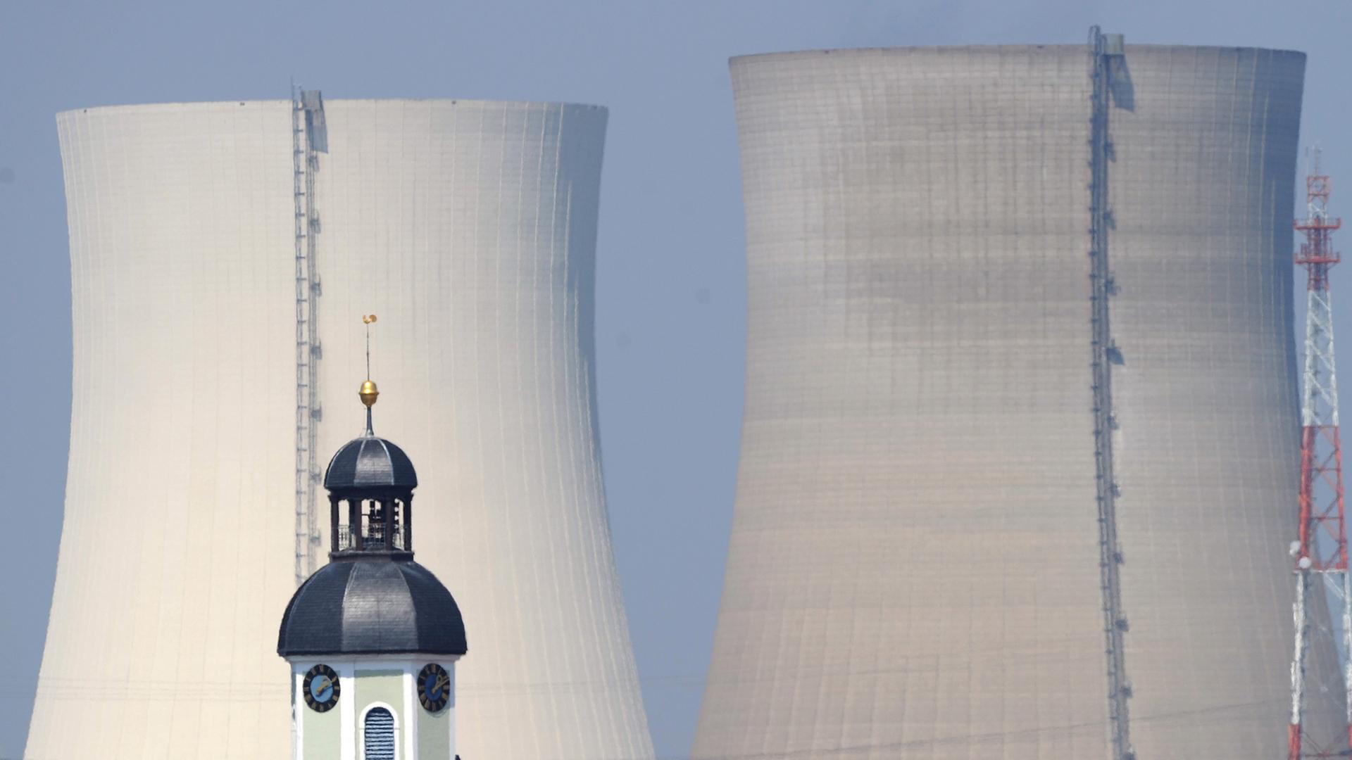 Hinter dem Kirchturm der Gemeinde Philippsburg und zwei roten Dächern von Wohnhäusern erheben sich die beiden Kühltürme des Atomkraftwerks Philippsburg. Hinter dem Kirchturm der Gemeinde Philippsburg und zwei roten Dächern von Wohnhäusern erheben sich die beiden Kühltürme des Atomkraftwerks Philippsburg.