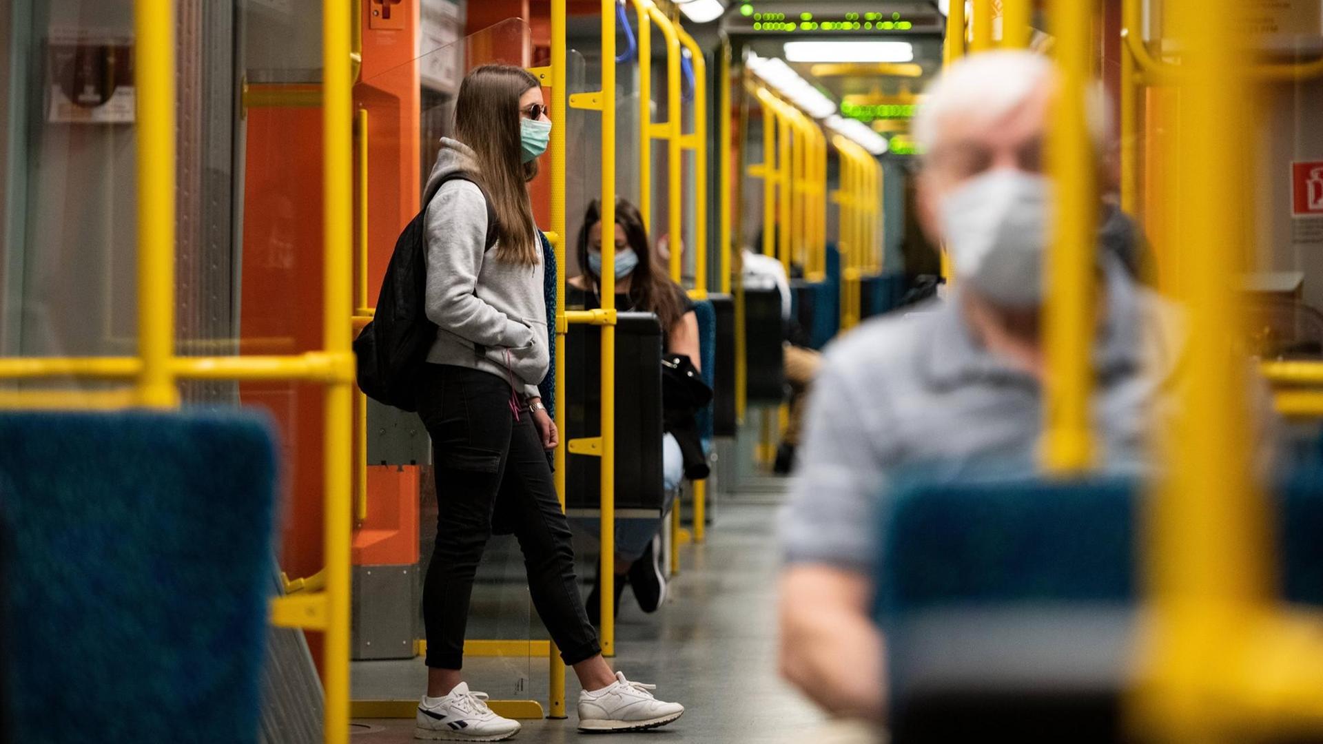 Blick in eine Bahn: Dort sitzen Menschen mit Masken vor dem Gesicht. Blick in eine Bahn: Dort sitzen Menschen mit Masken vor dem Gesicht.