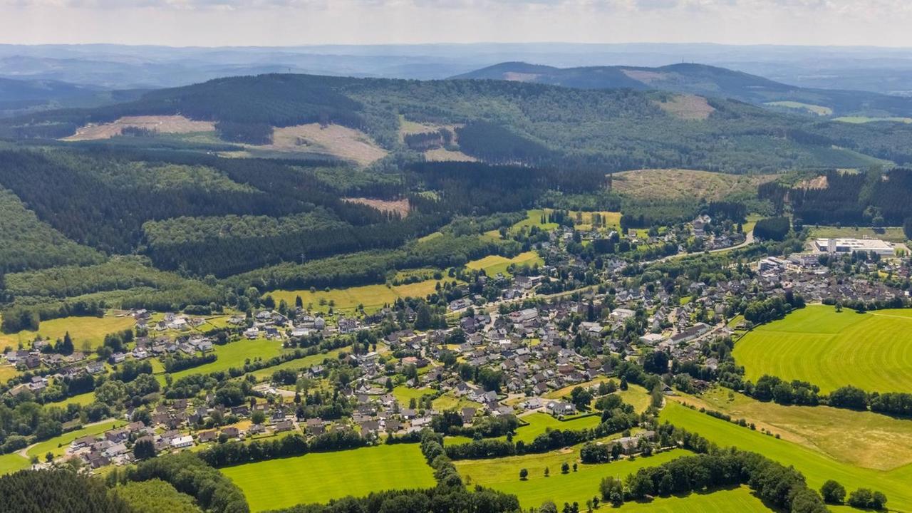 Luftbild des Ortes Wellschen-Ennest. Im Hintergrund liegt eine Hügelkette.
