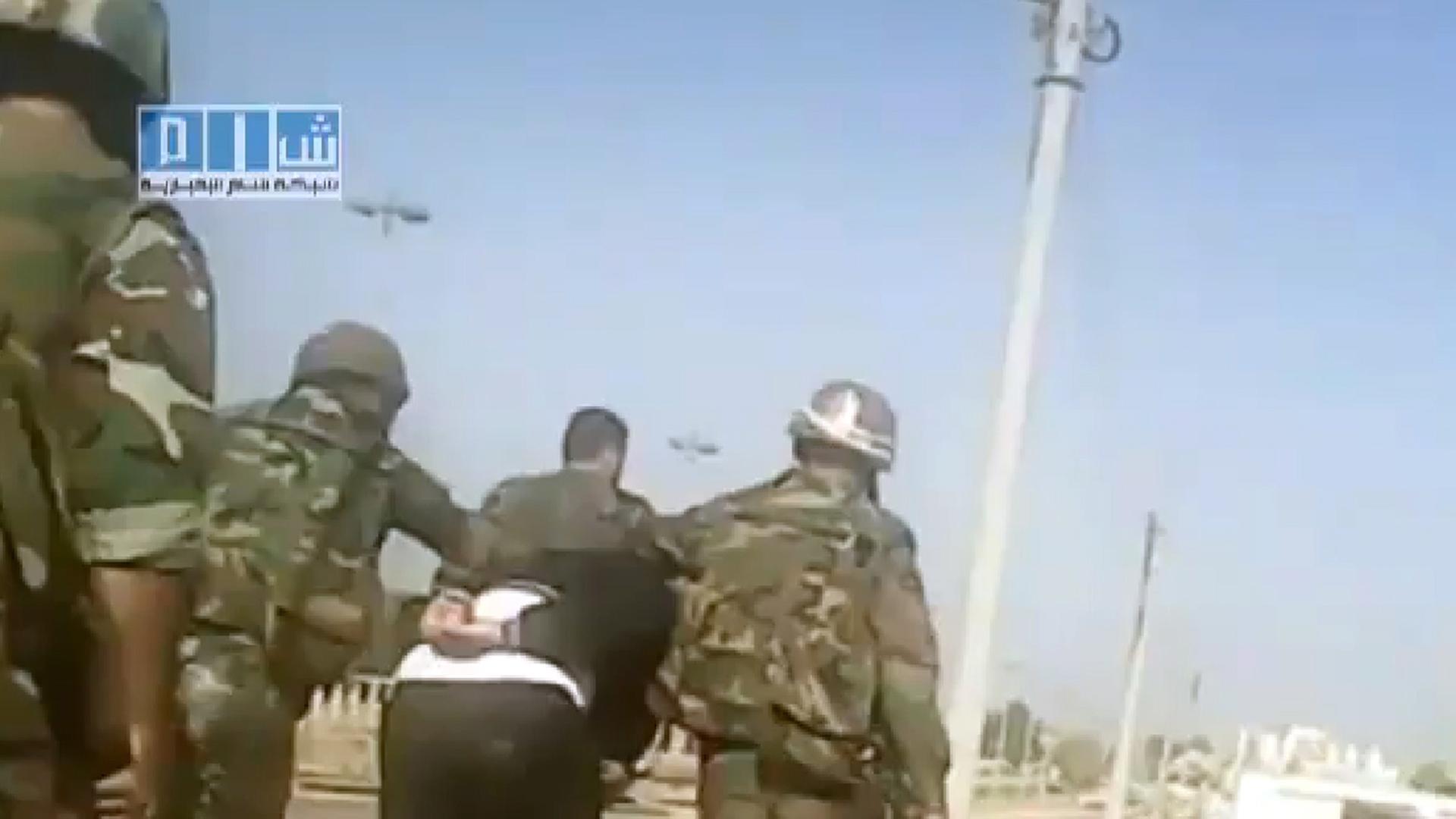 Syrische Soldaten führen einen Mann in Homs ab