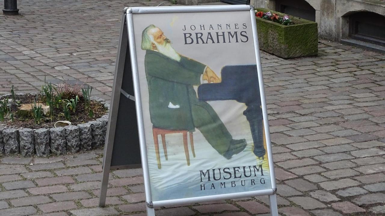 Ein Aufsteller mit einem Bild von Brahms steht auf einem Gehweg Ein Aufsteller mit einem Bild von Brahms steht auf einem Gehweg
