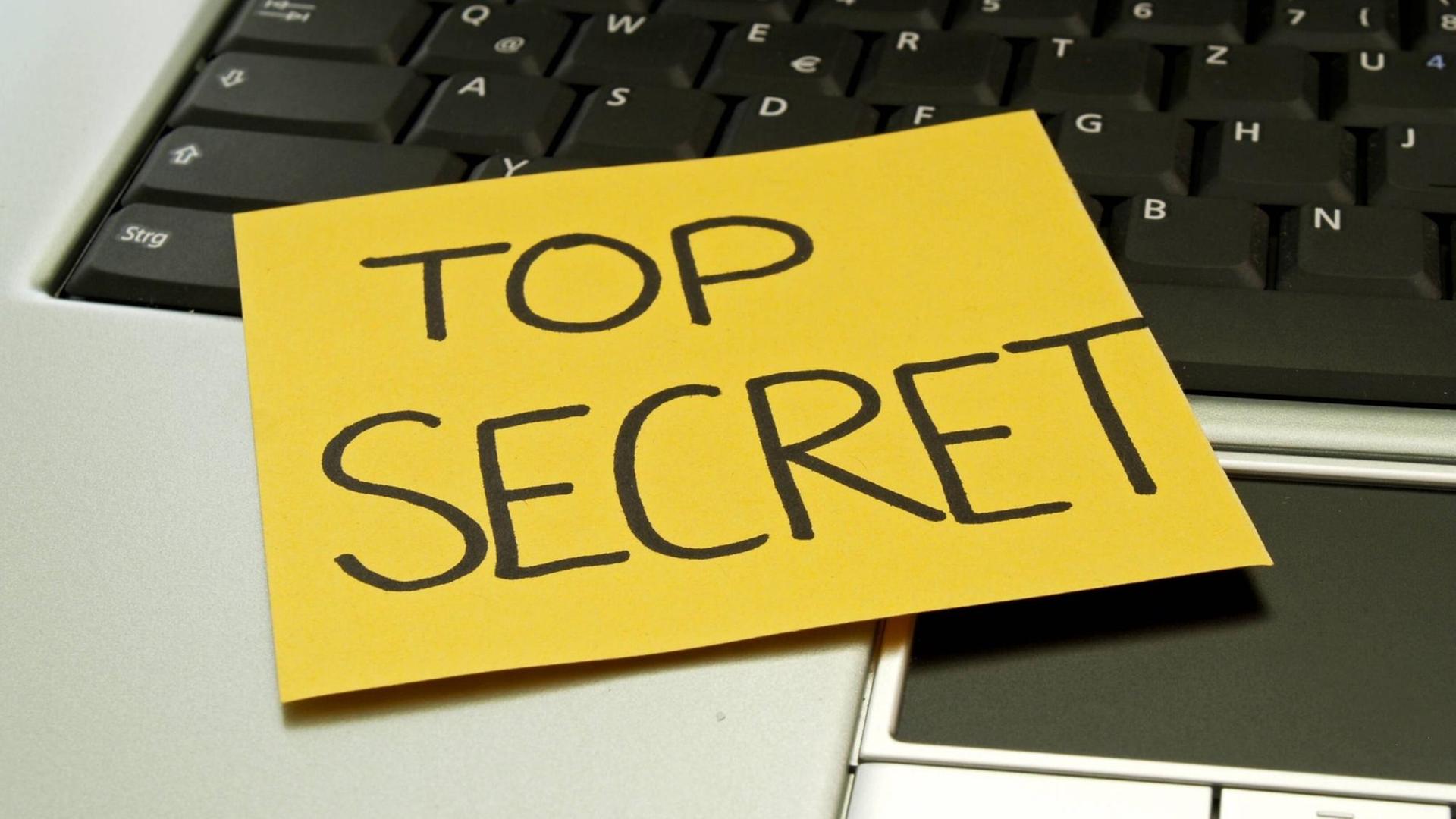 Auf einem Laptop klebt eine Notiz mit der Aufschrift "top secret"