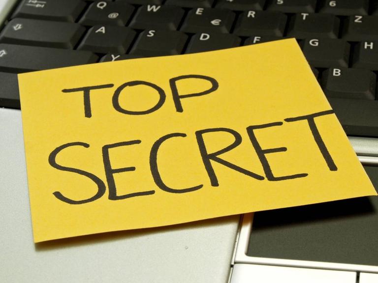 Auf einem Laptop klebt eine Notiz mit der Aufschrift "top secret"