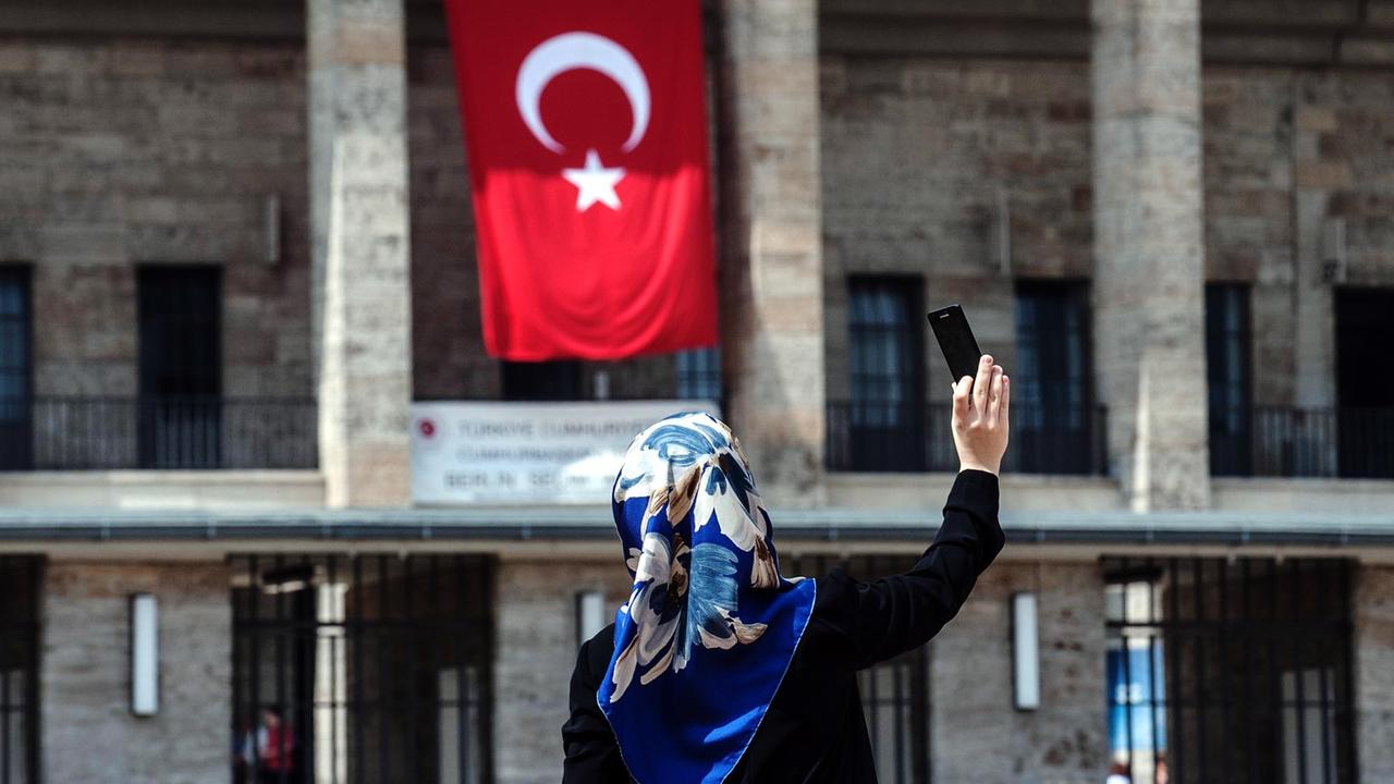 Eine Frau mit Kopftuch fotografiert sich selbst am 03.08.2014 vor dem Olympiastadion in Berlin, an dem eine türkische Fahne hängt. Im Olympiastadion ist ein Wahlzentrum für die türkische Präsidentenwahl in Deutschland. Erstmals können türkische Staatsangehörige in Deutschland an der türkischen Präsidentenwahl teilnehmen. Eine Frau mit Kopftuch fotografiert sich selbst am 03.08.2014 vor dem Olympiastadion in Berlin, an dem eine türkische Fahne hängt. Im Olympiastadion ist ein Wahlzentrum für die türkische Präsidentenwahl in Deutschland. Erstmals können türkische Staatsangehörige in Deutschland an der türkischen Präsidentenwahl teilnehmen.