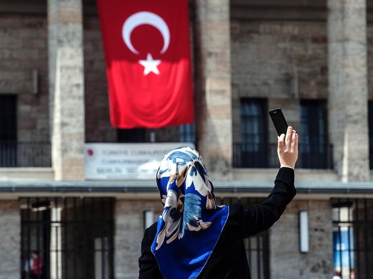 Eine Frau mit Kopftuch fotografiert sich selbst am 03.08.2014 vor dem Olympiastadion in Berlin, an dem eine türkische Fahne hängt. Im Olympiastadion ist ein Wahlzentrum für die türkische Präsidentenwahl in Deutschland. Erstmals können türkische Staatsange