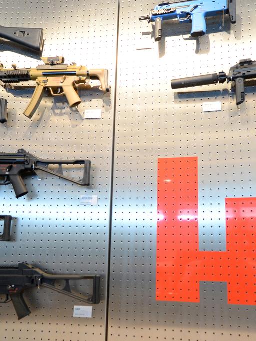 Verschiedene Ausführungen der Maschinenpistole MP5 hängen am Firmensitz des Waffenproduzenten Heckler & Koch in Oberndorf in einem Präsentationsraum an einer Wand neben einem Firmenlogo