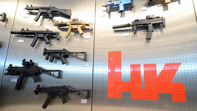 Verschiedene Ausführungen der Maschinenpistole MP5 hängen am Firmensitz des Waffenproduzenten Heckler & Koch in Oberndorf in einem Präsentationsraum an einer Wand neben einem Firmenlogo