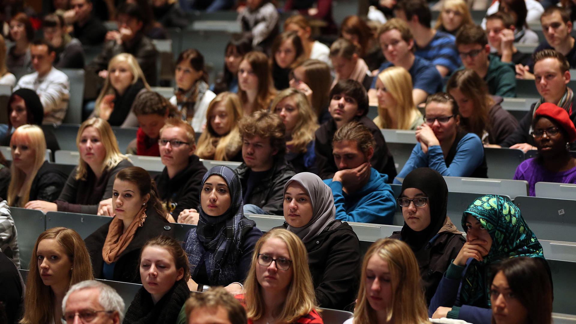Deutsche und internationale Studenten verfolgen in Köln in der Aula der Universität eine Vorlesung.