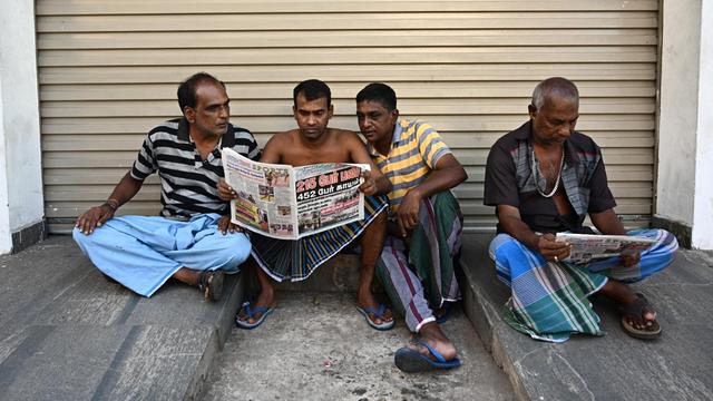 In der Nähe des St. Anthony's Shrine in Colombo sitzen vier Anwohner auf dem Boden und lesen Zeitungen, in denen über die Anschläge in Sri Lanka vom 21. April berichtet wird.