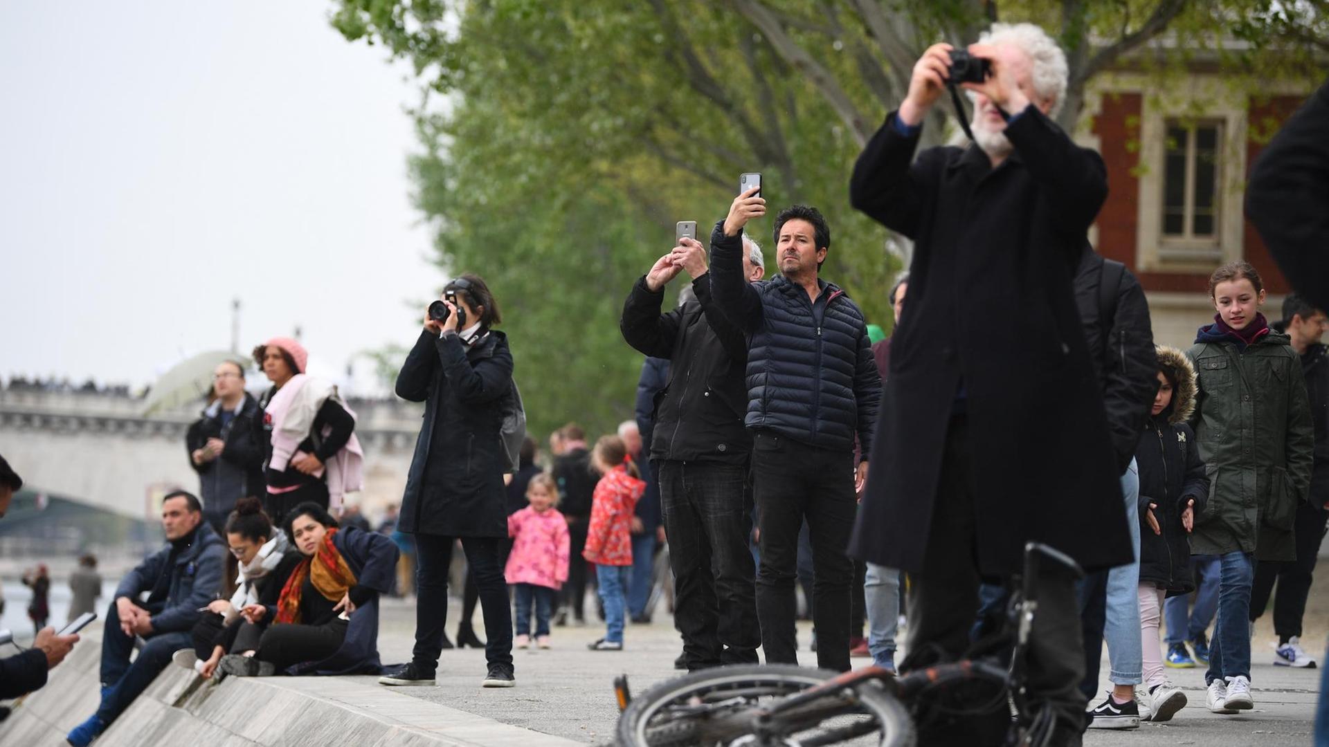 Menschen in Paris beobachten den Brand der von Notre-Dame.