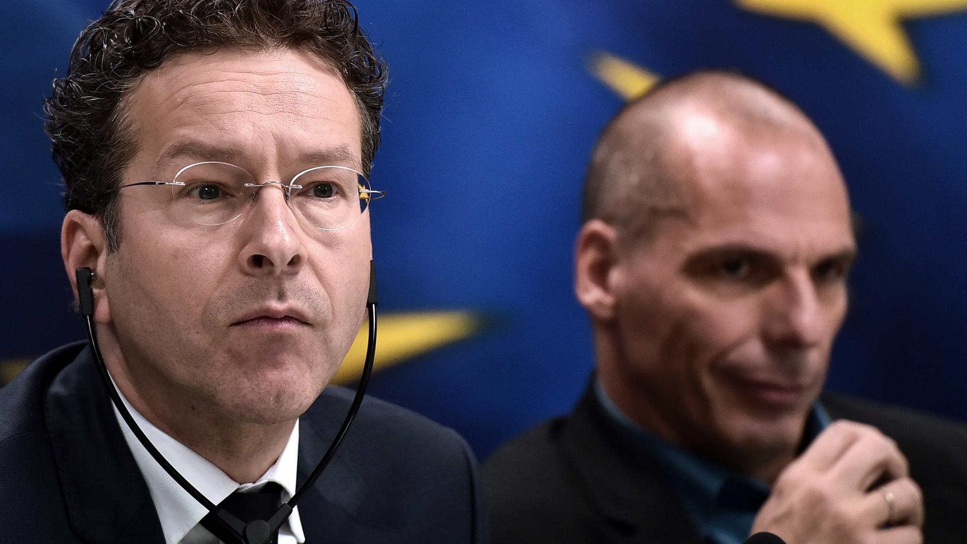 Eurogruppenchef Jeroen Dijsselbloem und der griechische Finanzminister Yanis Varoufakis bei einer Pressekonferenz in Athen. Dijsselbloen trägt einen Kopfhörer. Im Hintergrund ist die Europa-Fahne. Eurogruppenchef Jeroen Dijsselbloem und der griechische Finanzminister Yanis Varoufakis bei einer Pressekonferenz in Athen. Dijsselbloen trägt einen Kopfhörer. Im Hintergrund ist die Europa-Fahne.