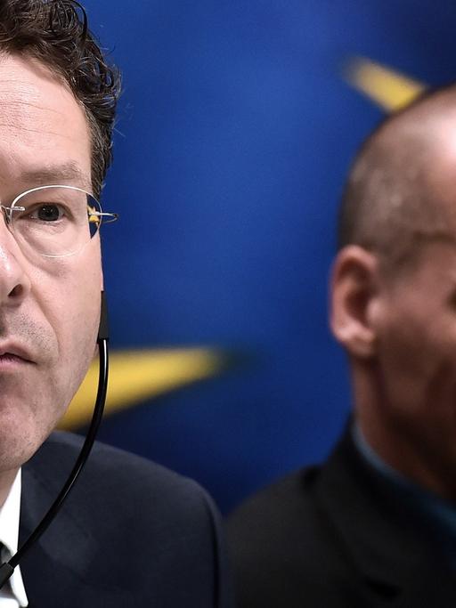 Eurogruppenchef Jeroen Dijsselbloem und der griechische Finanzminister Yanis Varoufakis bei einer Pressekonferenz in Athen. Dijsselbloen trägt einen Kopfhörer. Im Hintergrund ist die Europa-Fahne.